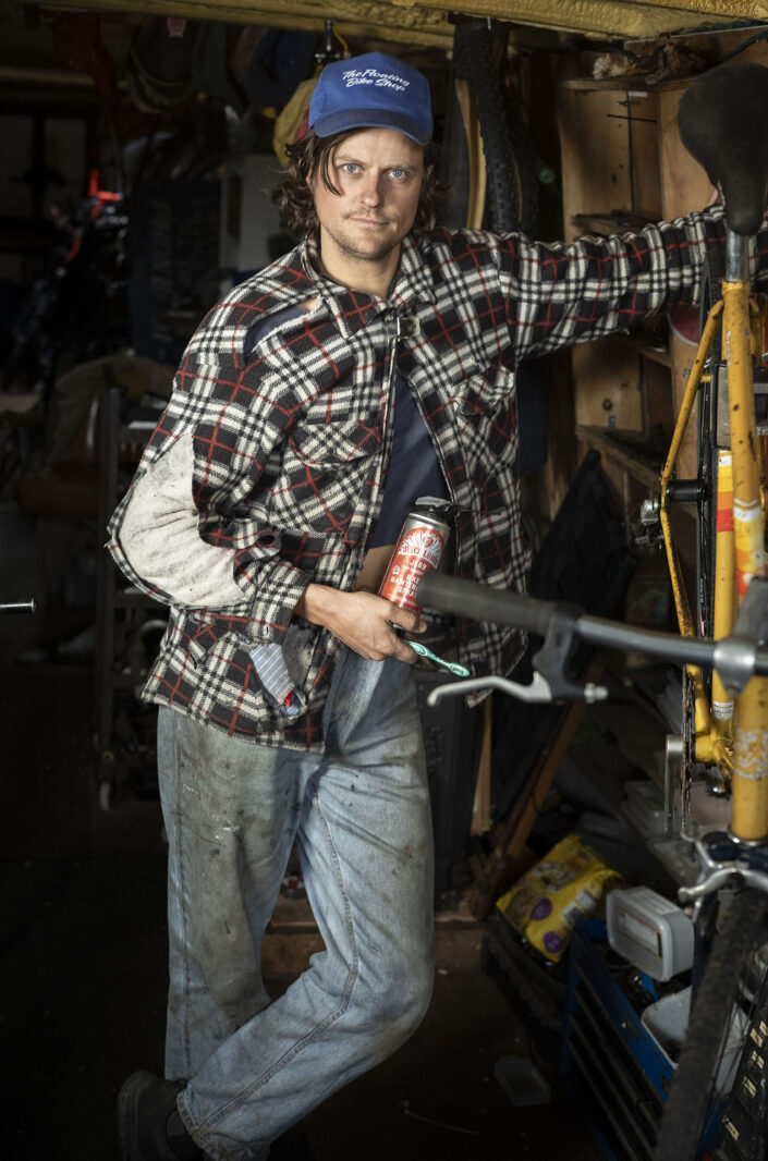 Portrait of Sam Skinner who runs his own bike shop on a barge in East London photographed by London based portrait photographer Jeff Gilbert